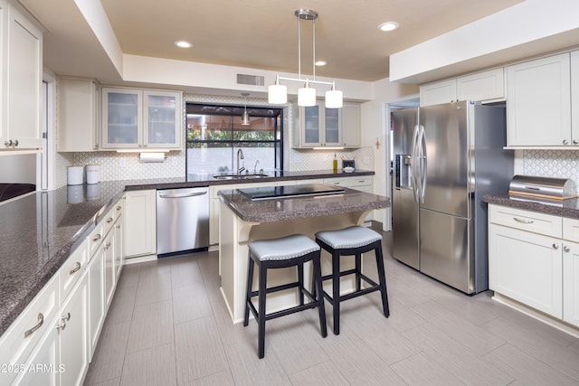 kitchen with visible vents, decorative backsplash, a kitchen breakfast bar, stainless steel appliances, and a sink