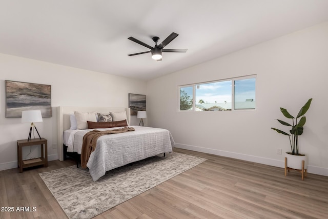 bedroom with baseboards, light wood-type flooring, ceiling fan, and vaulted ceiling