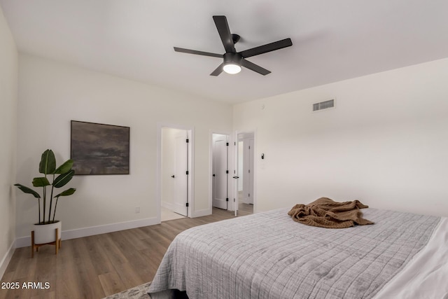 bedroom featuring baseboards, visible vents, a ceiling fan, and wood finished floors