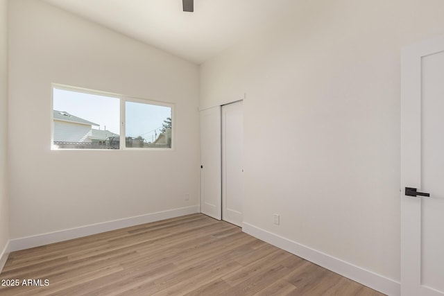 spare room with a ceiling fan, light wood-style floors, and baseboards