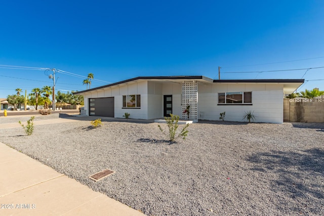 view of front facade featuring concrete driveway, a garage, and fence