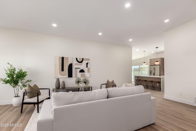 living area with baseboards, light wood-type flooring, and recessed lighting