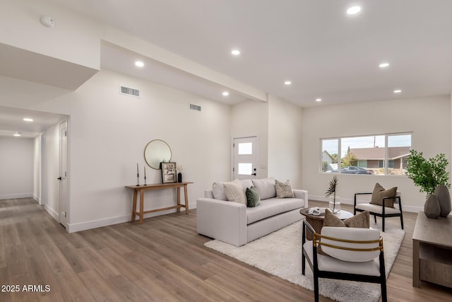 living room featuring baseboards, visible vents, wood finished floors, and recessed lighting