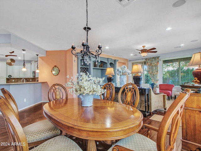 dining space with ceiling fan with notable chandelier and hardwood / wood-style flooring