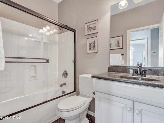 full bathroom featuring a chandelier, toilet, vanity, and bath / shower combo with glass door