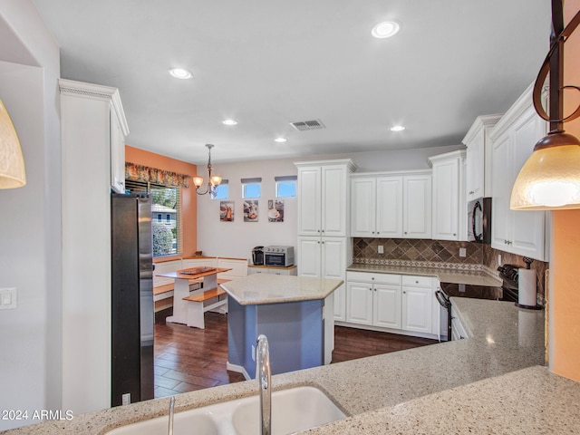 kitchen with dark wood-type flooring, white cabinetry, stainless steel appliances, decorative light fixtures, and light stone countertops