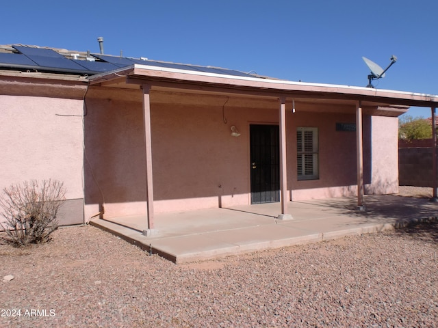 back of property with a patio and solar panels