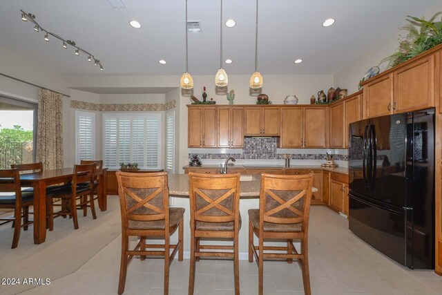 kitchen with black fridge, decorative light fixtures, decorative backsplash, and light tile patterned floors