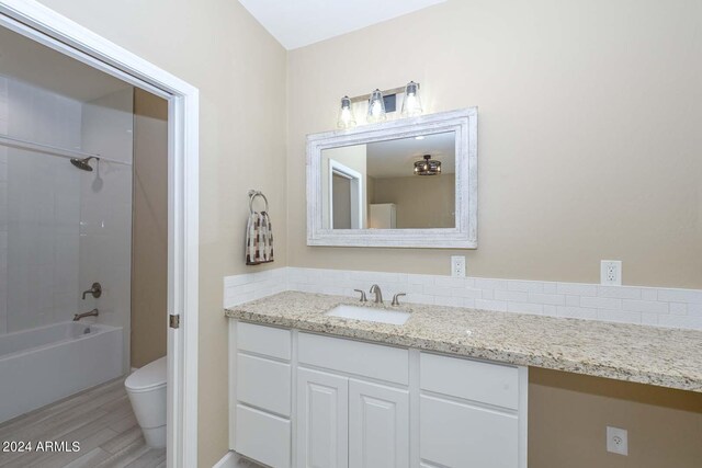 full bathroom featuring tiled shower / bath, toilet, and vanity