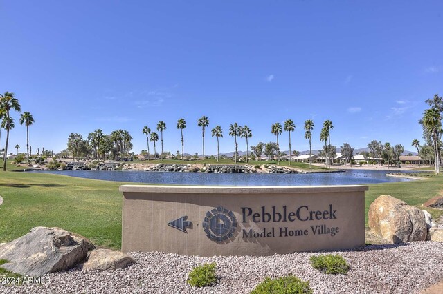 community sign featuring a lawn and a water view