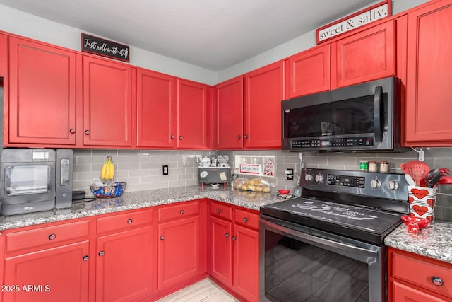 kitchen with light stone counters, backsplash, and stainless steel range with electric cooktop