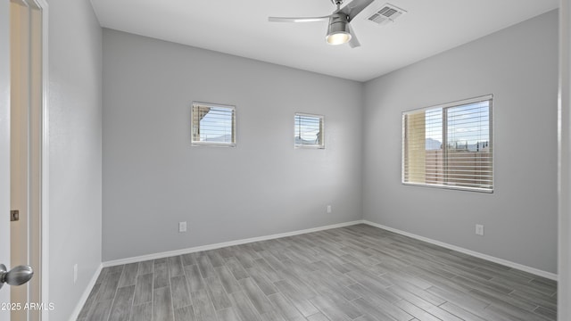 unfurnished room featuring a ceiling fan, a wealth of natural light, wood finished floors, and visible vents