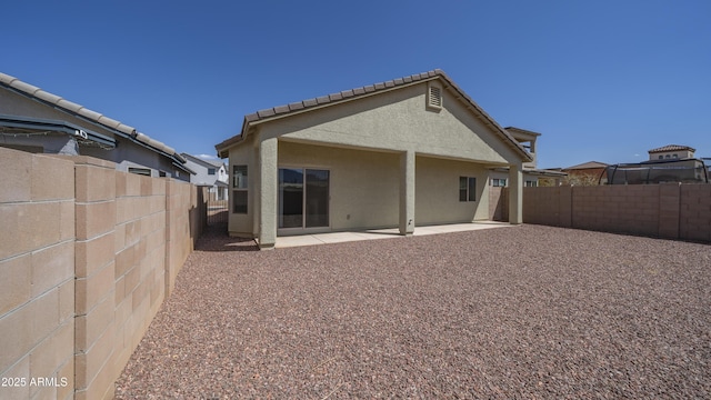 rear view of house with a fenced backyard, stucco siding, and a patio area