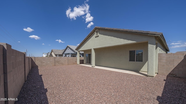 rear view of property featuring a fenced backyard, stucco siding, and a patio