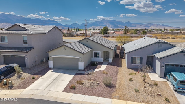 view of front facade featuring a garage, concrete driveway, a standing seam roof, stucco siding, and a mountain view
