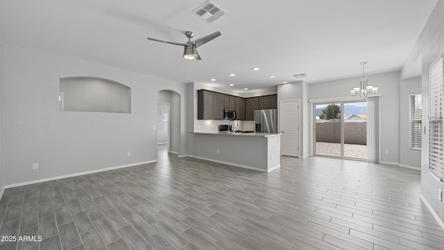 unfurnished living room with visible vents, baseboards, recessed lighting, arched walkways, and ceiling fan with notable chandelier