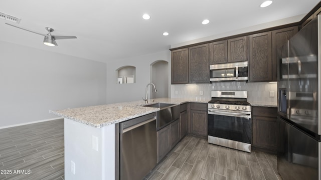 kitchen featuring backsplash, a sink, a peninsula, stainless steel appliances, and visible vents