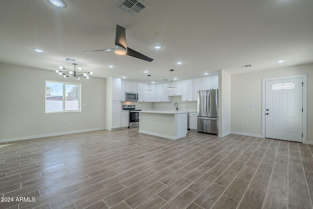 kitchen with light hardwood / wood-style floors, a kitchen island, pendant lighting, and appliances with stainless steel finishes