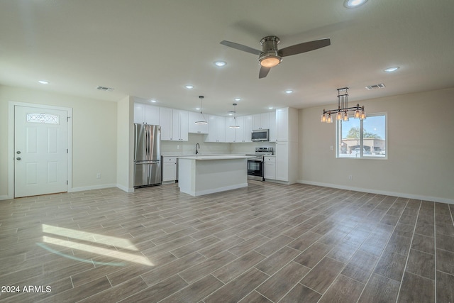 kitchen with light wood-type flooring, stainless steel appliances, white cabinetry, and a kitchen island