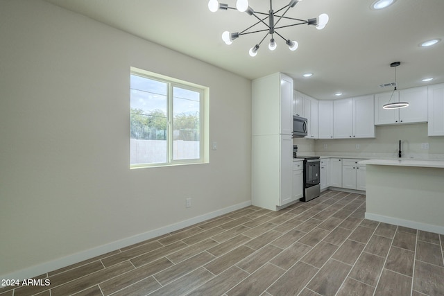 kitchen featuring stainless steel appliances, an inviting chandelier, light hardwood / wood-style flooring, pendant lighting, and white cabinets