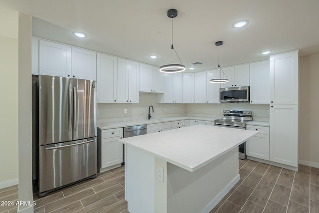 kitchen featuring white cabinets, decorative light fixtures, a kitchen island, and appliances with stainless steel finishes