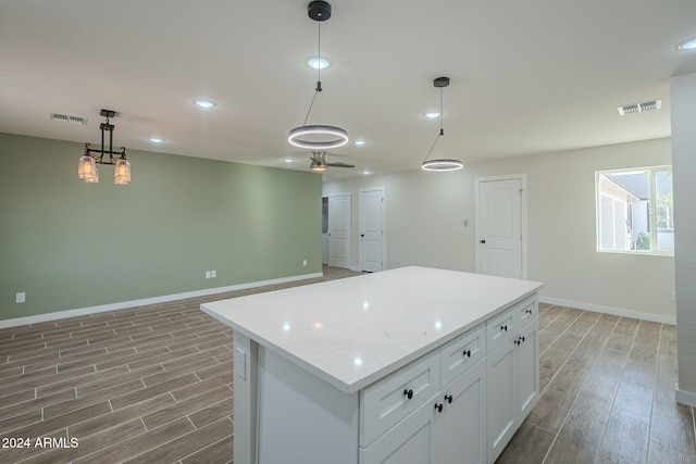 kitchen featuring ceiling fan, decorative light fixtures, white cabinets, hardwood / wood-style floors, and a center island