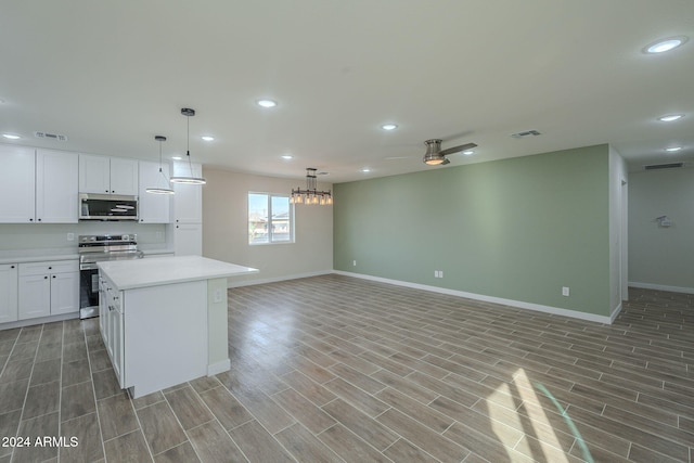 kitchen with light hardwood / wood-style flooring, ceiling fan, appliances with stainless steel finishes, a kitchen island, and white cabinetry