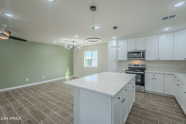 kitchen with a center island, dark wood-type flooring, white cabinets, hanging light fixtures, and appliances with stainless steel finishes