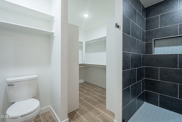 bathroom with tiled shower and toilet