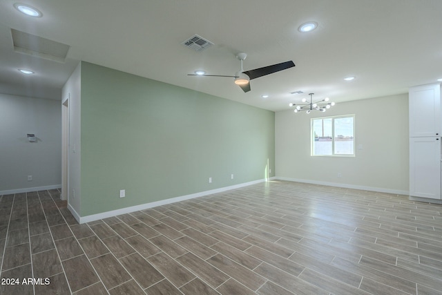 empty room with hardwood / wood-style floors and ceiling fan with notable chandelier