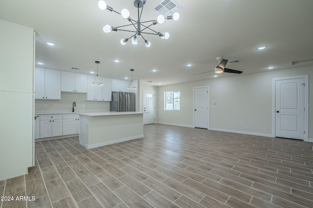 kitchen with stainless steel fridge, a kitchen island, decorative light fixtures, light hardwood / wood-style flooring, and white cabinetry