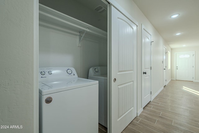 laundry room with light hardwood / wood-style floors and washing machine and clothes dryer