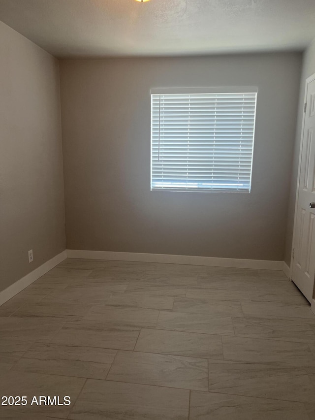 unfurnished room with baseboards