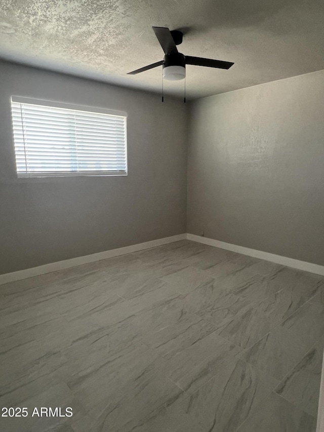 empty room featuring baseboards, a textured ceiling, and a ceiling fan