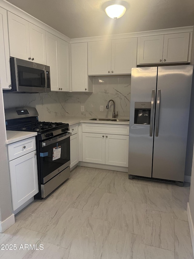 kitchen featuring light countertops, stainless steel appliances, marble finish floor, white cabinetry, and a sink