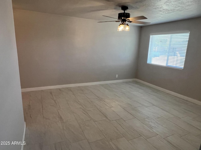 spare room with a ceiling fan, baseboards, and a textured ceiling