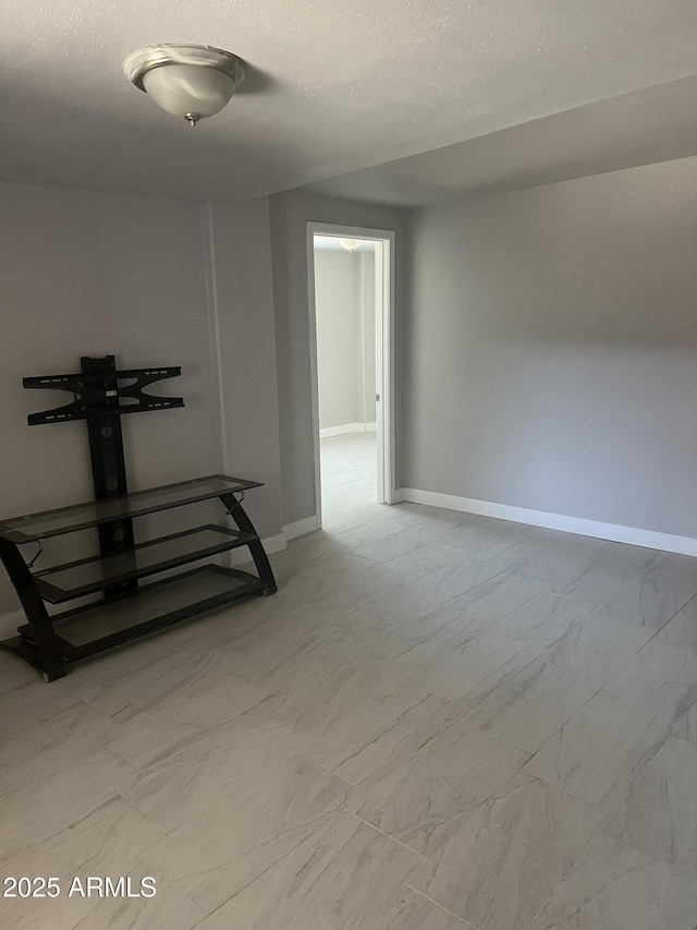 interior space with baseboards, a textured ceiling, and marble finish floor