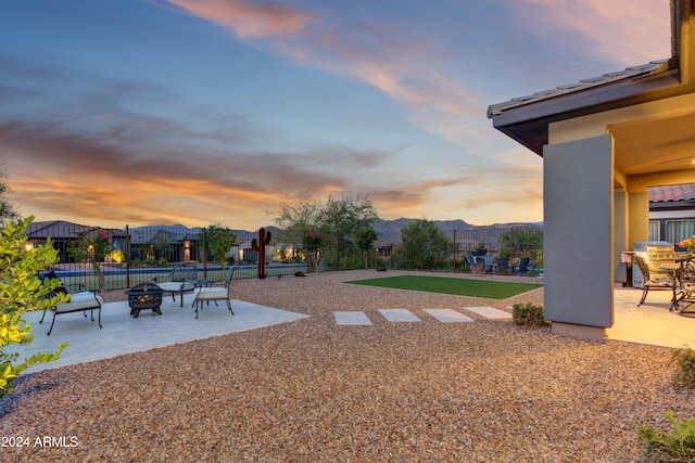 yard at dusk featuring a mountain view, an outdoor fire pit, and a patio area