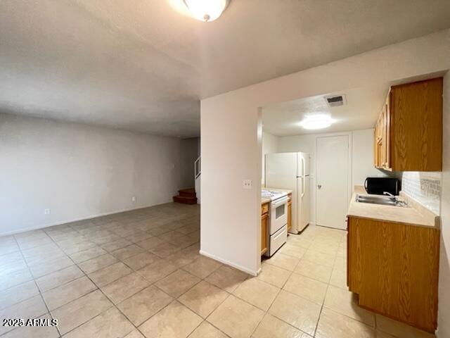 kitchen featuring brown cabinets, white appliances, light countertops, light tile patterned floors, and visible vents