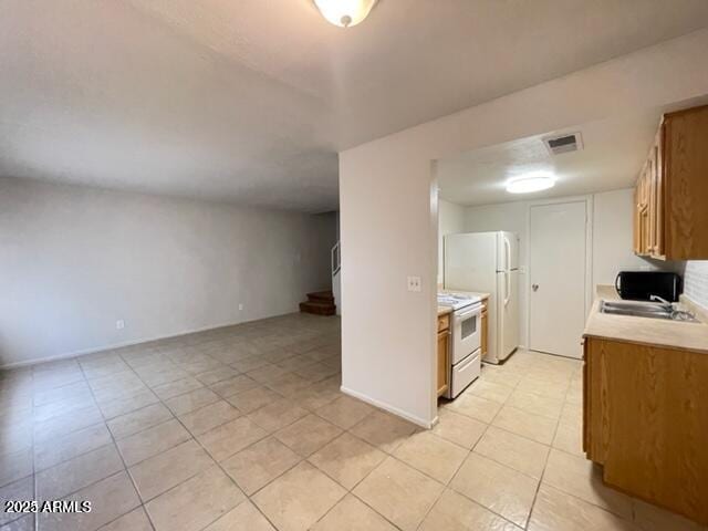 kitchen featuring brown cabinetry, visible vents, light tile patterned floors, light countertops, and white electric range oven