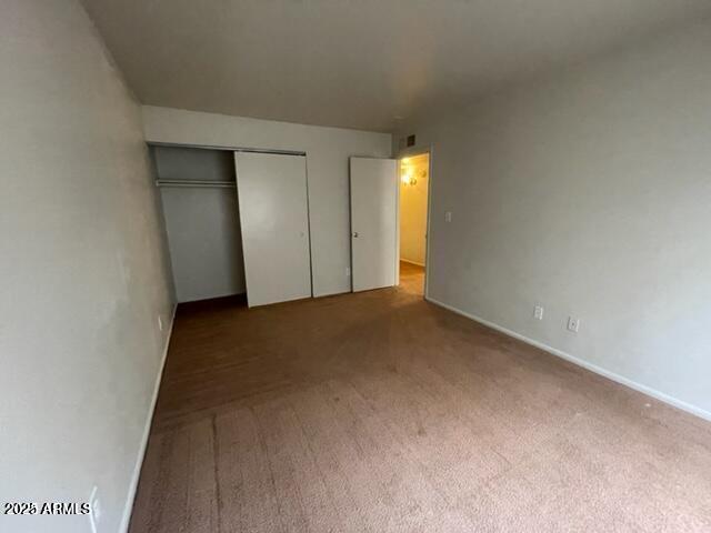 unfurnished bedroom featuring baseboards, carpet, and a closet