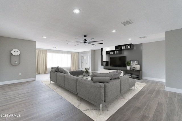 living room featuring a textured ceiling, light hardwood / wood-style flooring, and ceiling fan