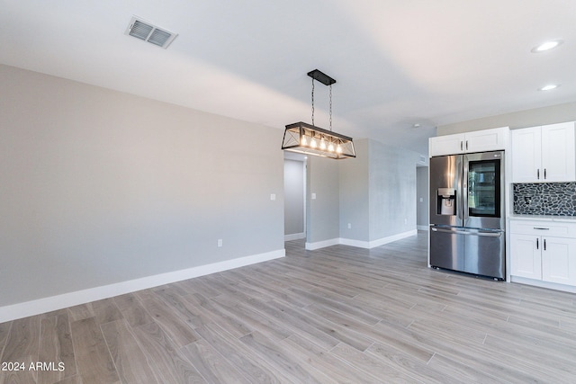 kitchen with stainless steel fridge, white cabinetry, light hardwood / wood-style flooring, and decorative light fixtures