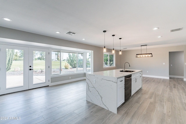 kitchen with light wood-type flooring, light stone countertops, white cabinetry, sink, and a kitchen island with sink