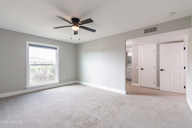 interior space with ceiling fan, connected bathroom, and light carpet