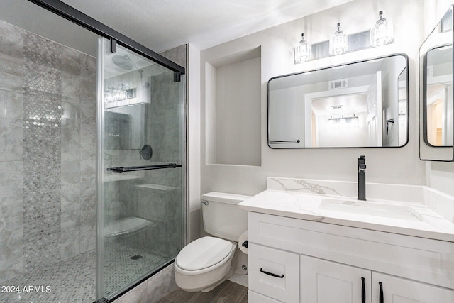 bathroom featuring vanity, toilet, wood-type flooring, and a shower with shower door