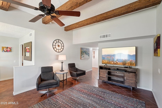 sitting room featuring ceiling fan, beam ceiling, dark tile patterned flooring, and a textured ceiling