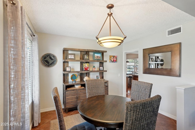 tiled dining room featuring a textured ceiling