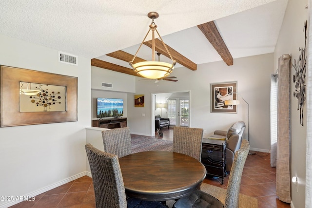 tiled dining room with a textured ceiling, beam ceiling, and french doors