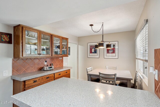 kitchen with decorative backsplash, a textured ceiling, and decorative light fixtures